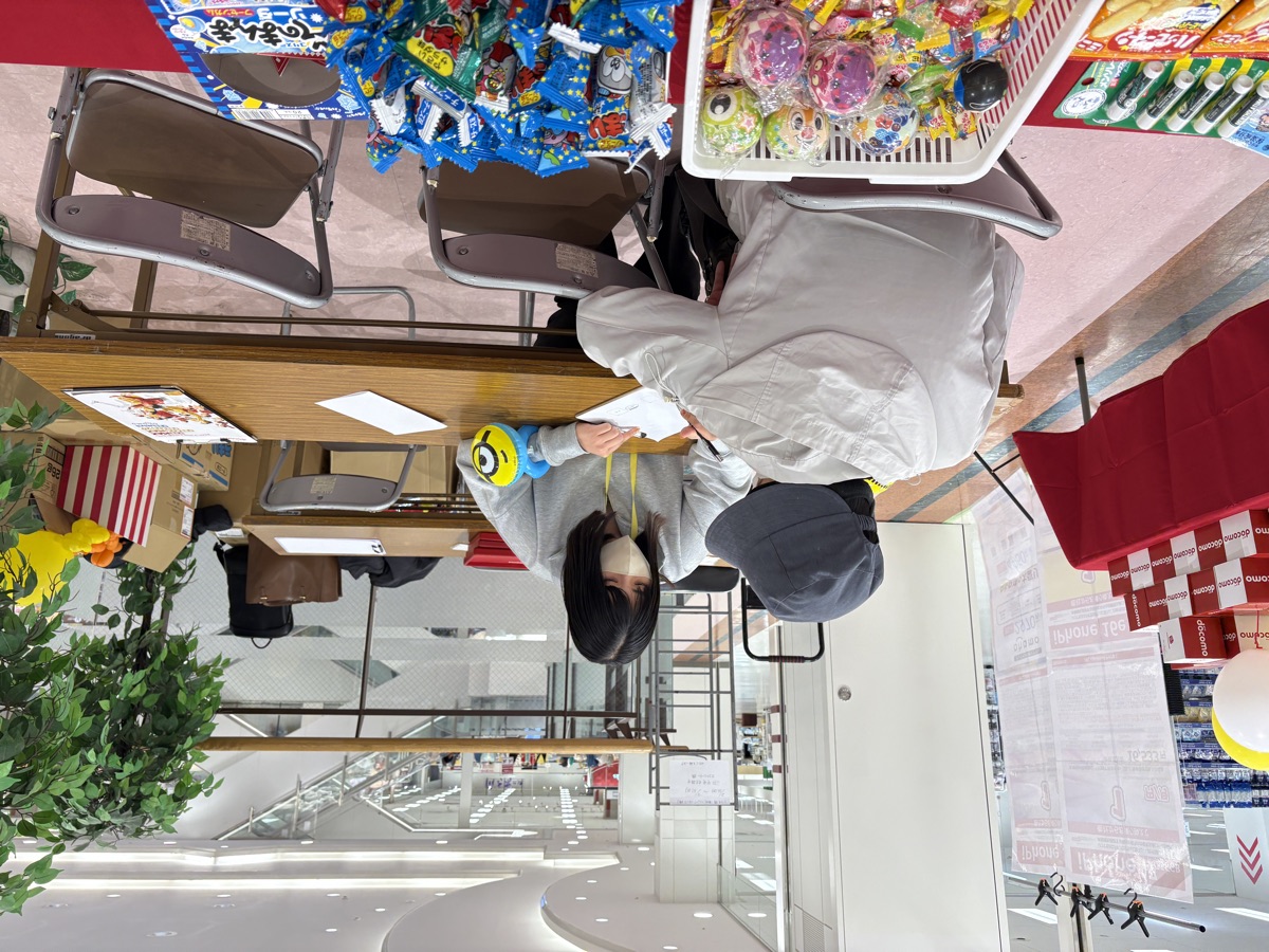 家電量販店のブースでお客様に説明する学生インターン
